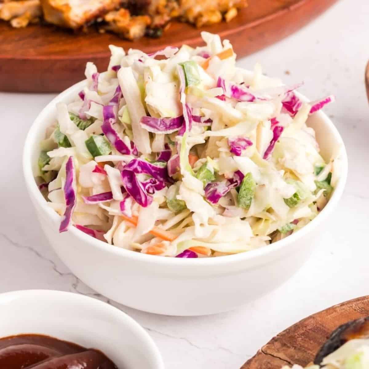 A white bowl full of spicy coleslaw with cabbage, onions, and jalapeno peppers.