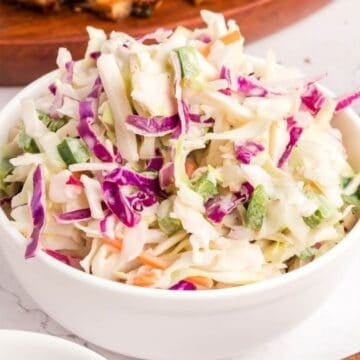 Spicy coleslaw piled high in a white bowl.