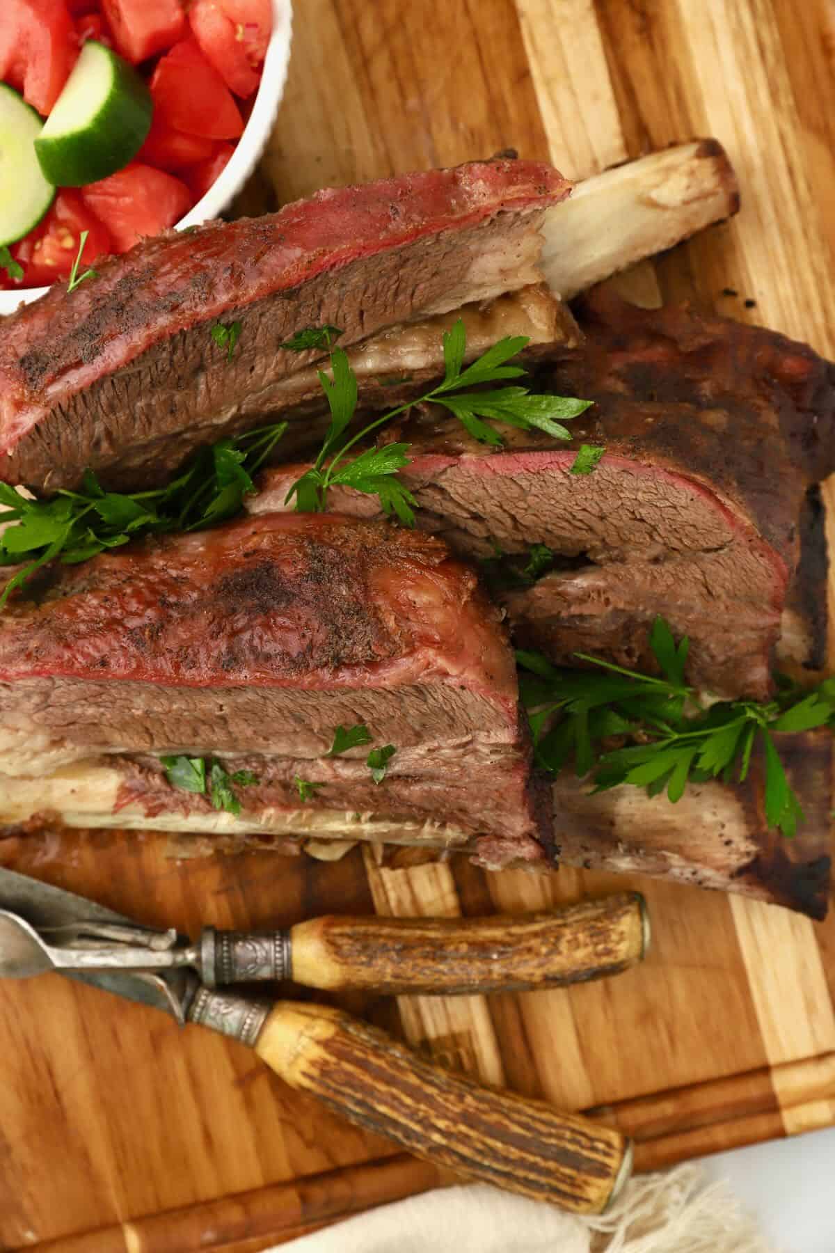 Smoked beef short ribs with a visible smoke ring sliced on a cutting board.