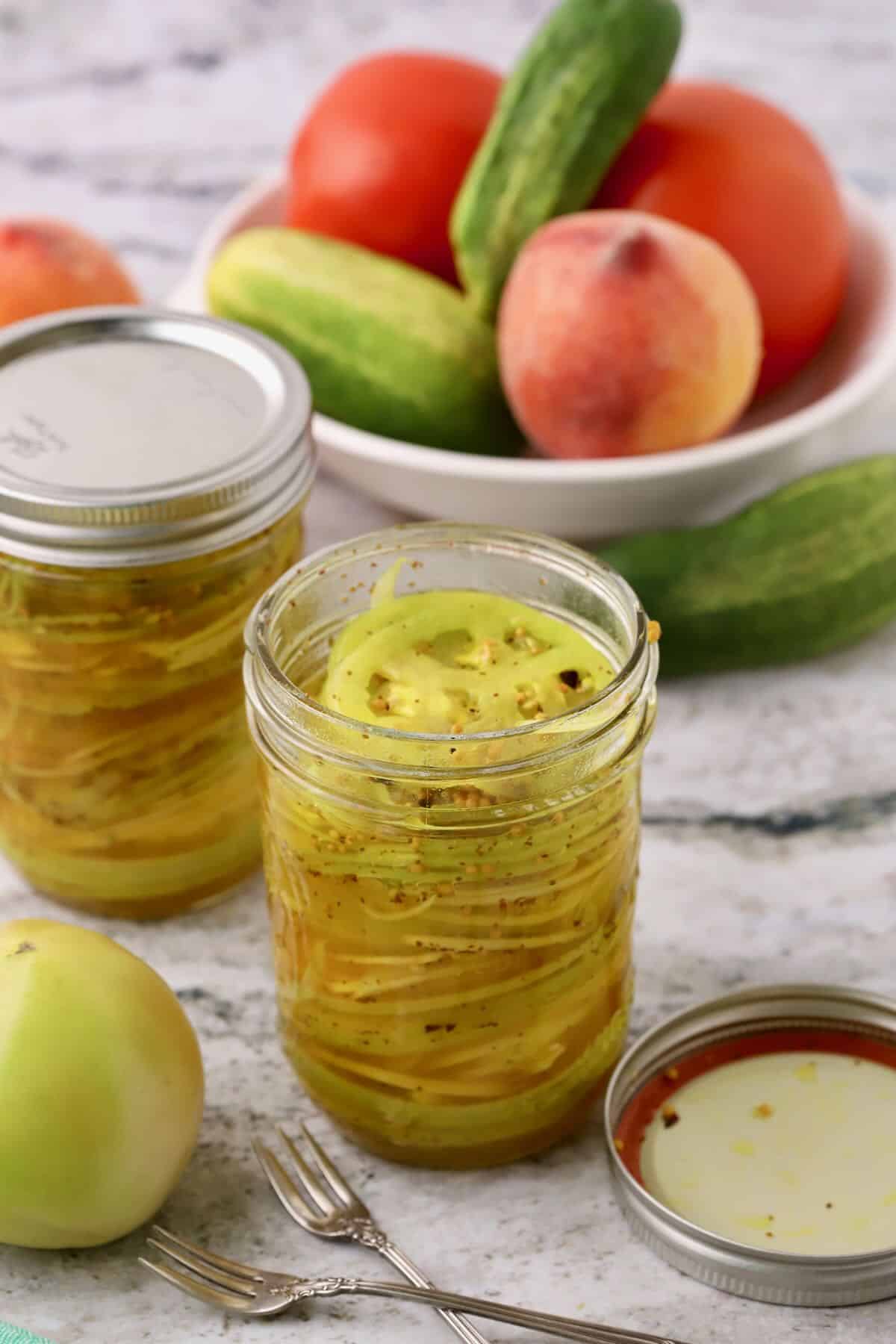Sliced green tomatoes and onions in pint-sized jars with brine.