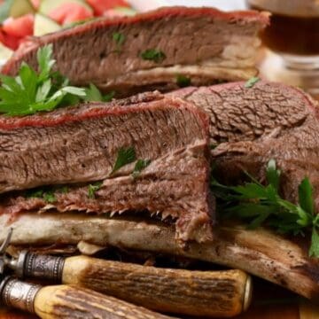 Four sliced smoked beef short ribs on a cutting board.