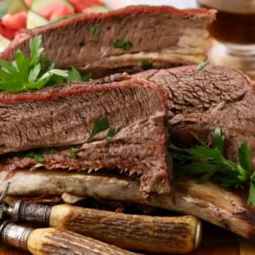 Four sliced smoked beef short ribs on a cutting board.