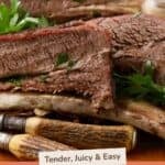 Four sliced smoked beef short ribs piled high on a cutting board.