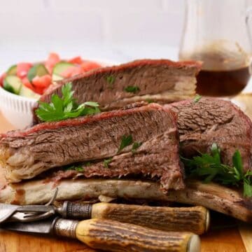 Smoked beef short ribs, sliced and piled high on a cutting board.