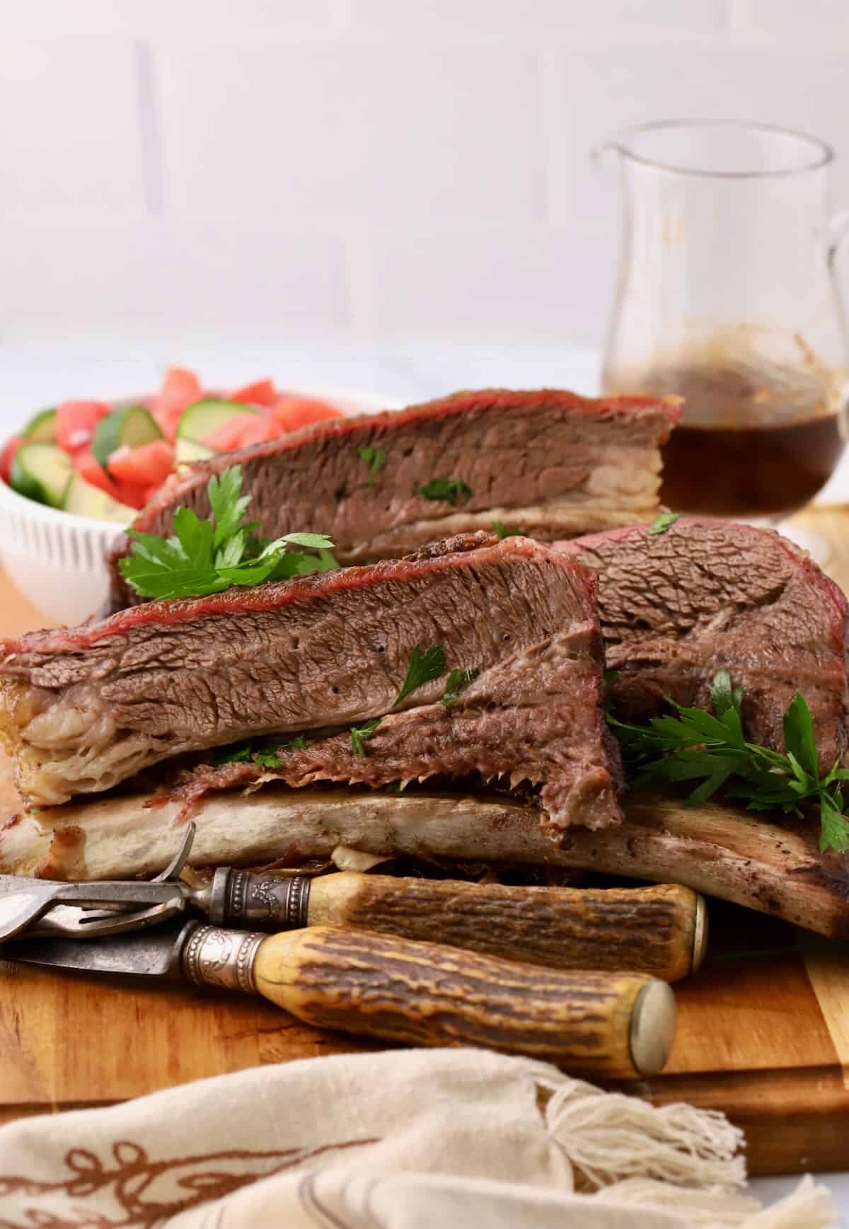 Smoked beef short ribs sliced and piled high on a cutting board. 