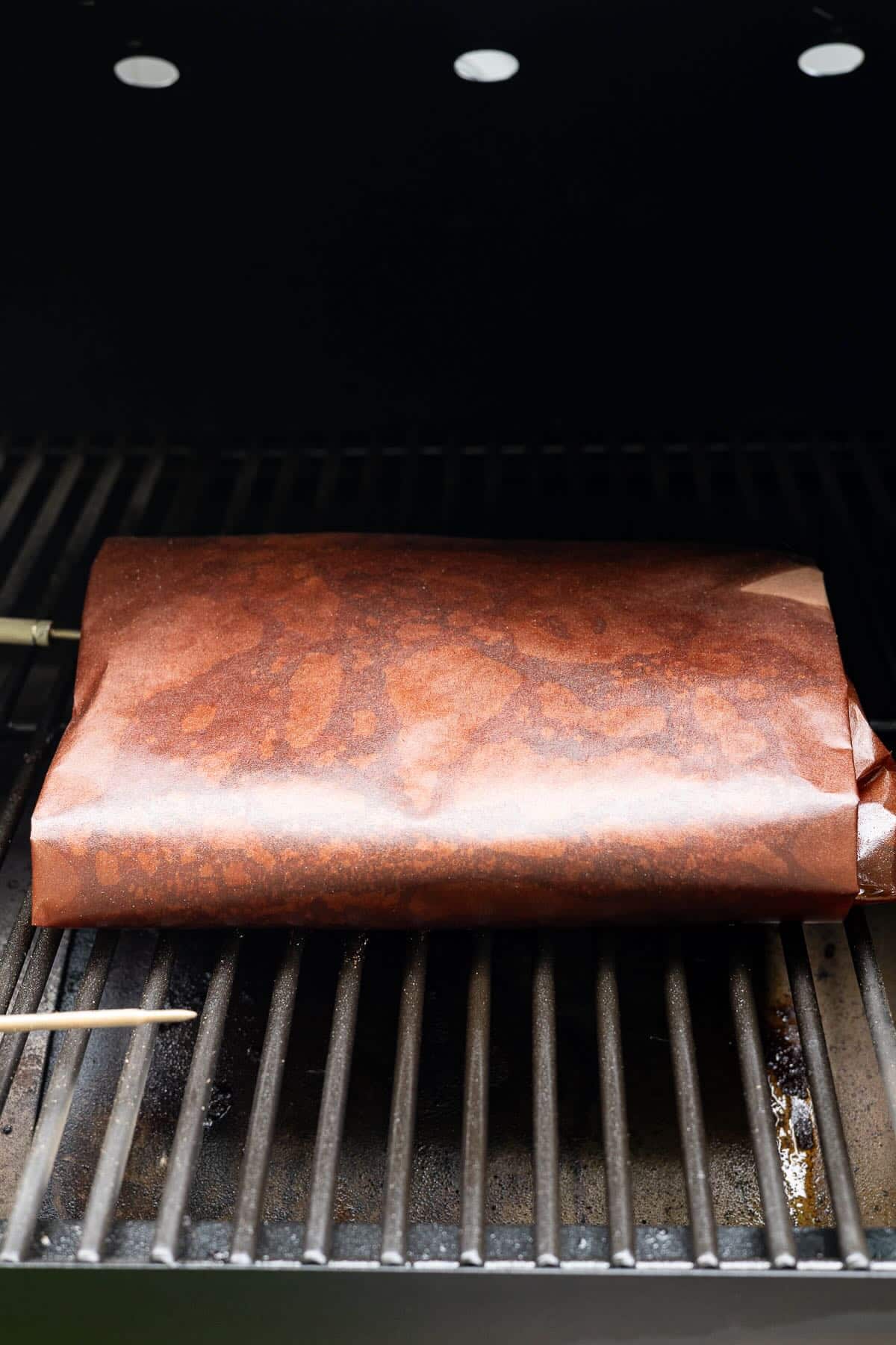 A wrapped chuck roast in a smoker, continuing to cook.