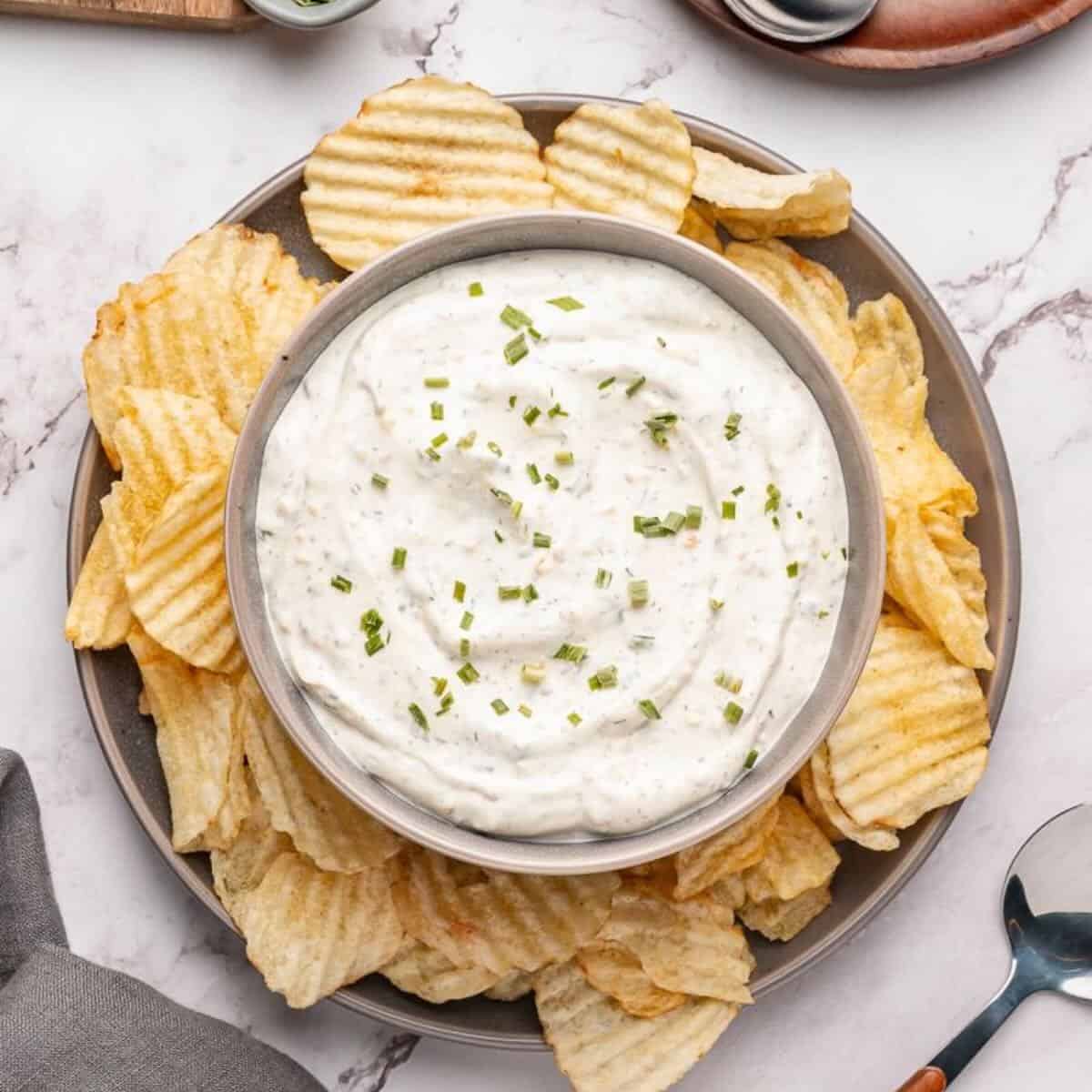 Beau Monde Dip in a bowl surrounded by ruffled potato chips.