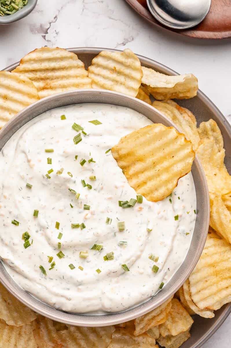 A large bowl of Beau Monde Dip surrounded by ridged potato chips.
