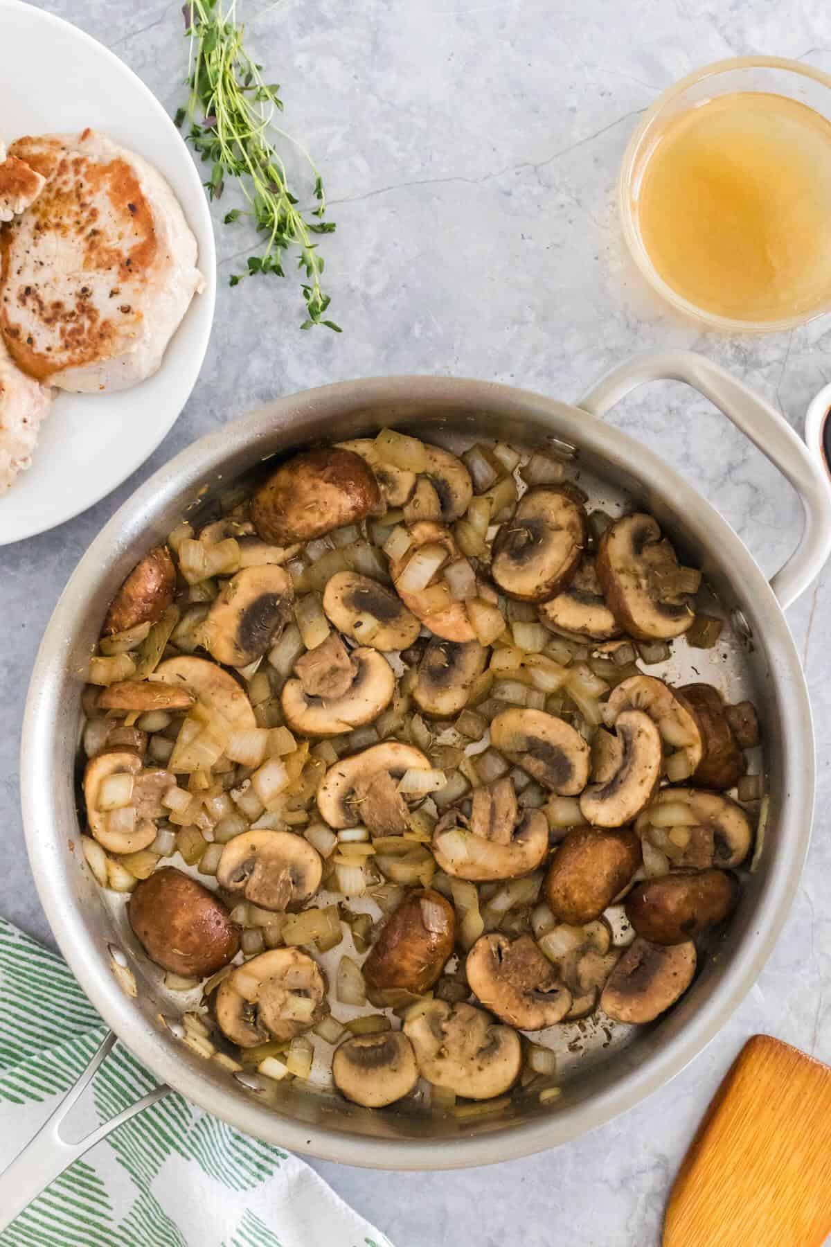 Sliced mushrooms cooking in a skillet.