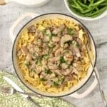 Beef Stroganoff made with leftover steak served over egg noodles in a skillet, garnished with chopped parsley.
