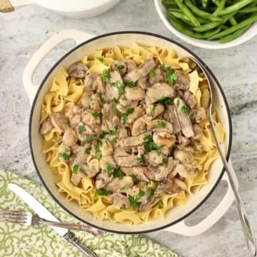 Beef Stroganoff made with leftover steak served over egg noodles in a skillet, garnished with chopped parsley.