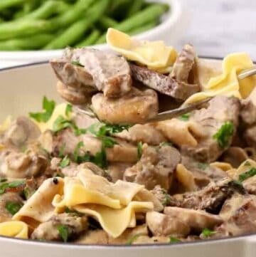 Creamy leftover steak stroganoff served over egg noodles with mushrooms and parsley