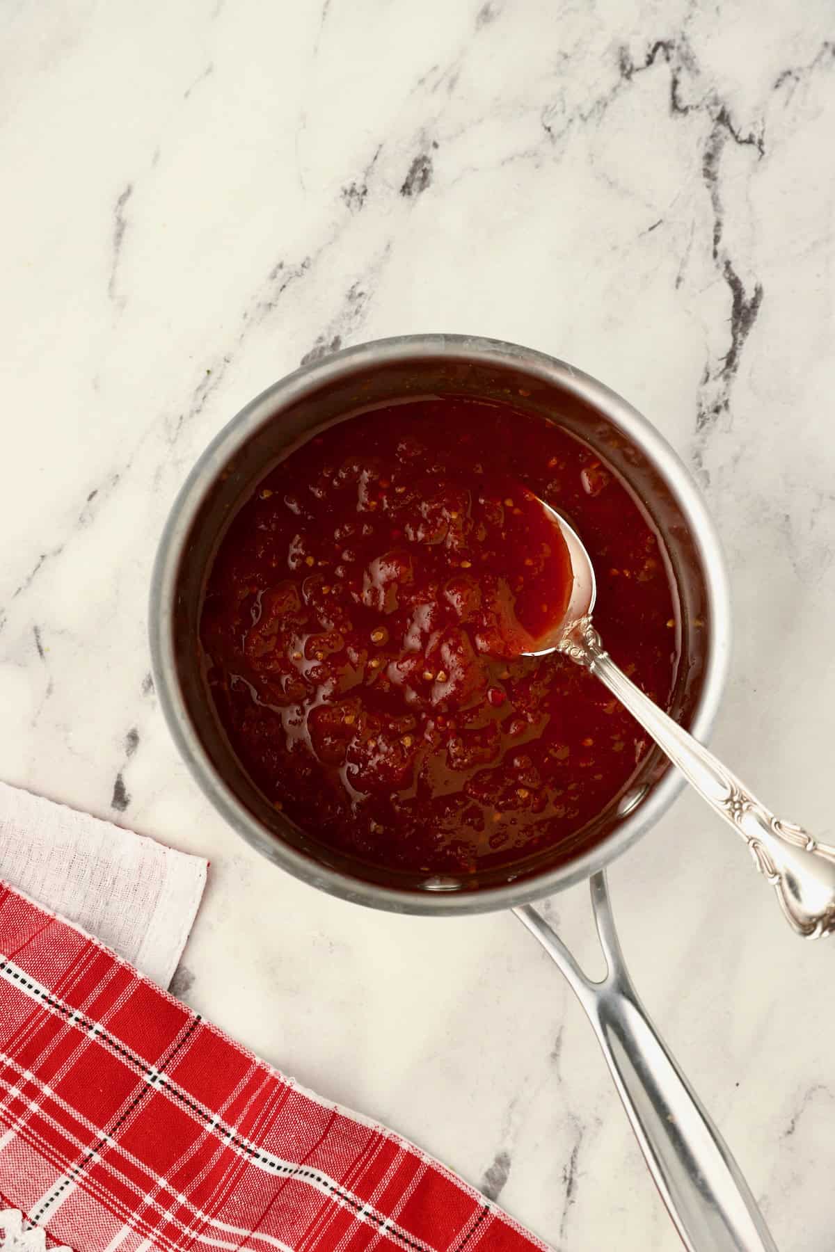 Tomato jam is simmering on the stove.
