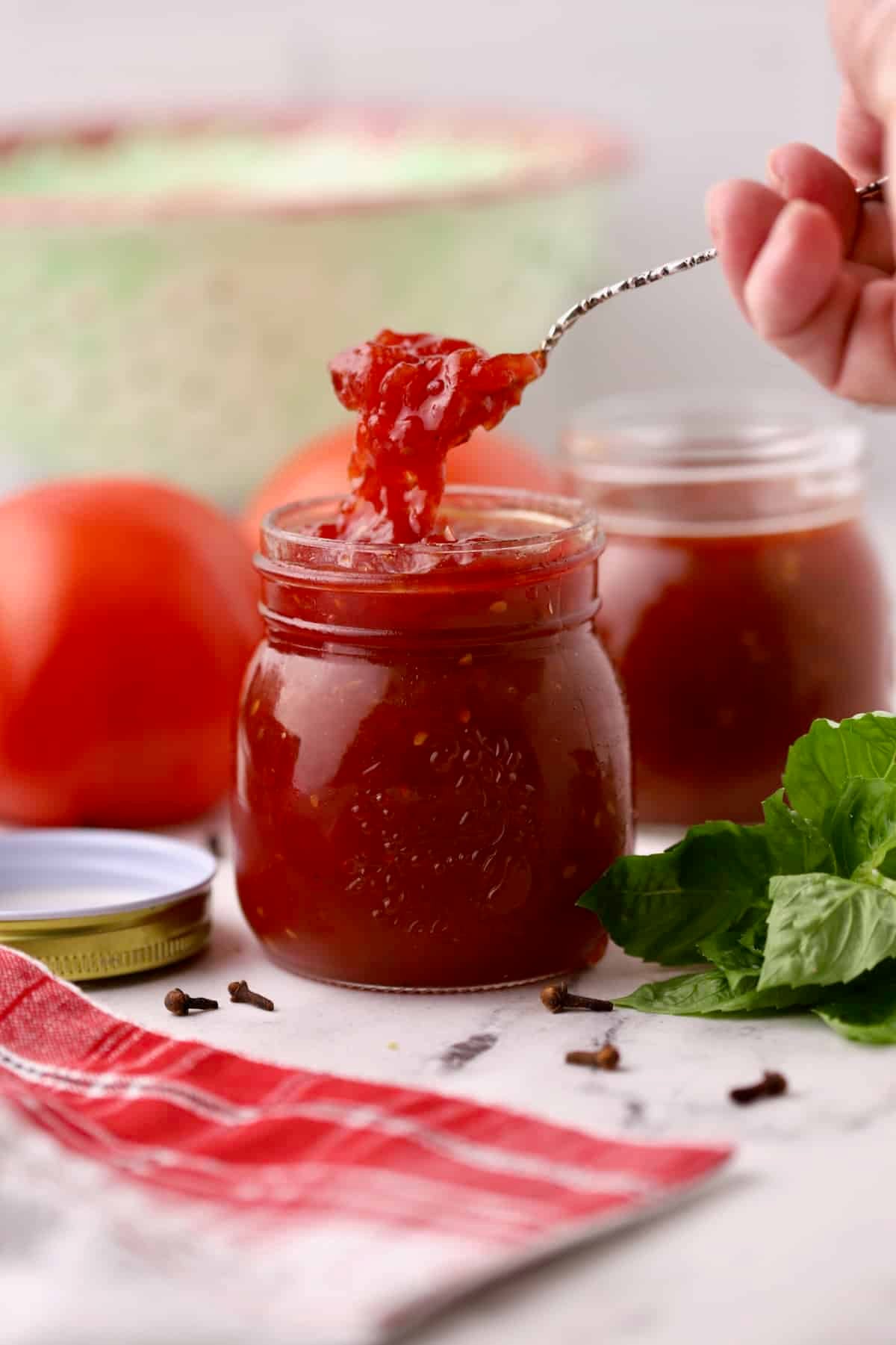 Two jars of easy homemade tomato jam with a spoonful lifted from the jar.