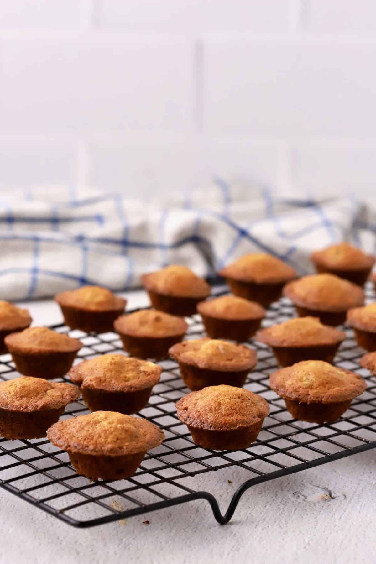 Banana nut mini muffins are cooling on a metal rack.