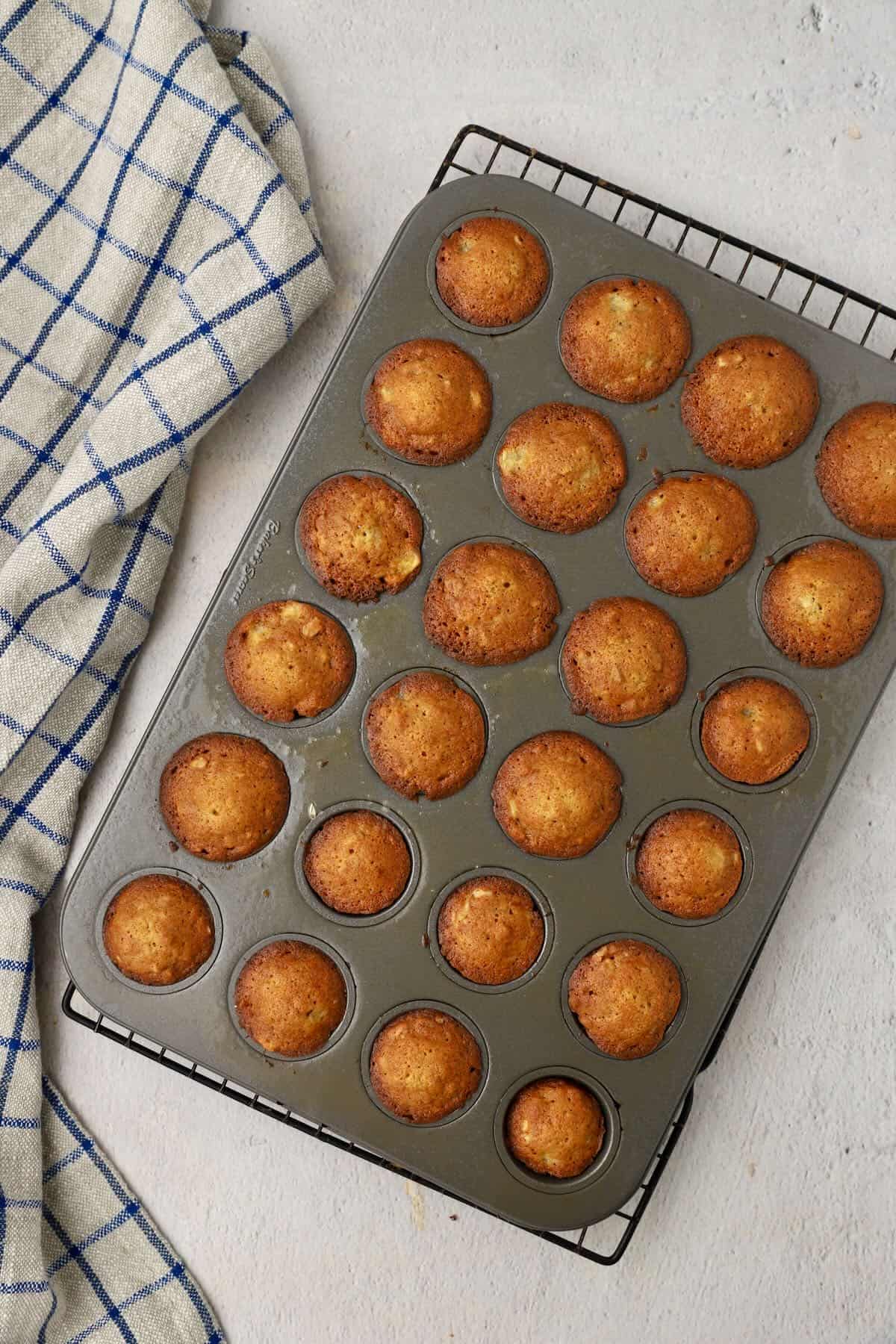 A mini muffin pan with baked banana nut mini muffins.