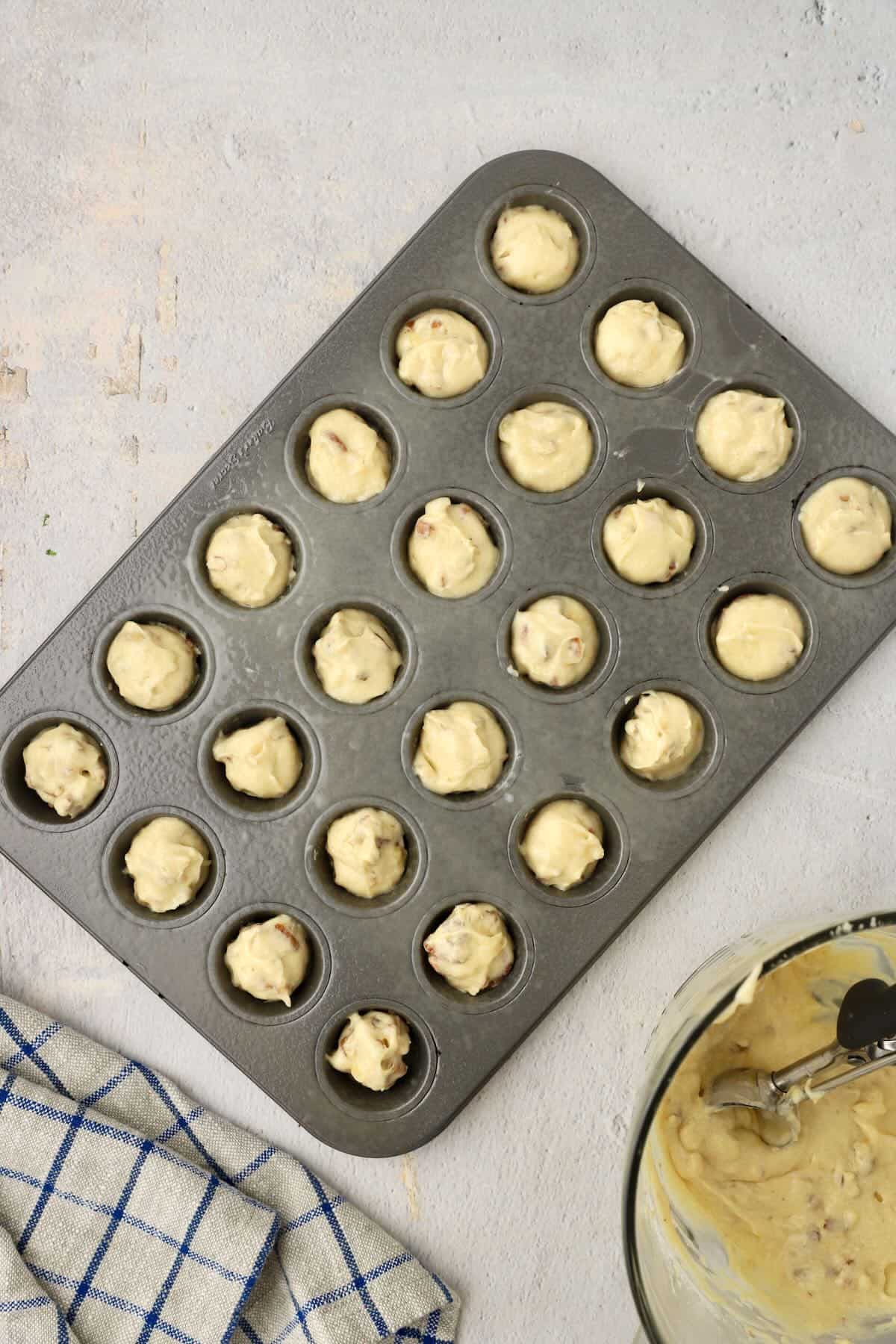 A mini muffin pan with muffin batter in the cups.