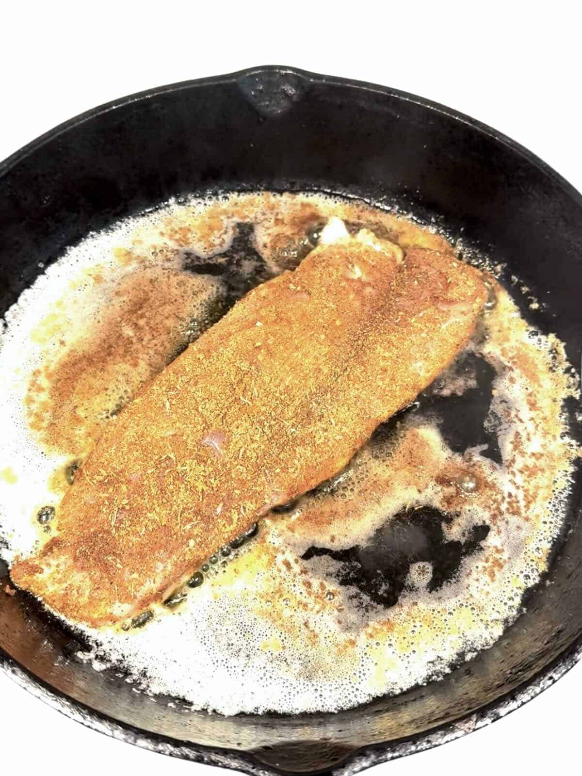 Blackened redfish cooking in a cast iron skillet.