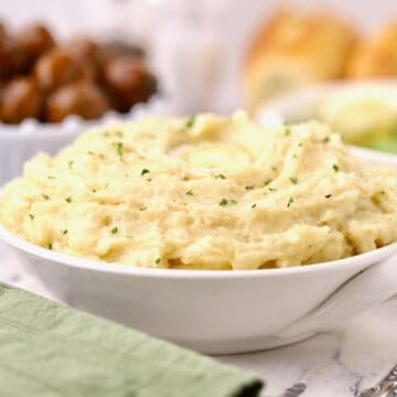 A large white bowl full of mashed potatoes that had been cooked in a crock pot.