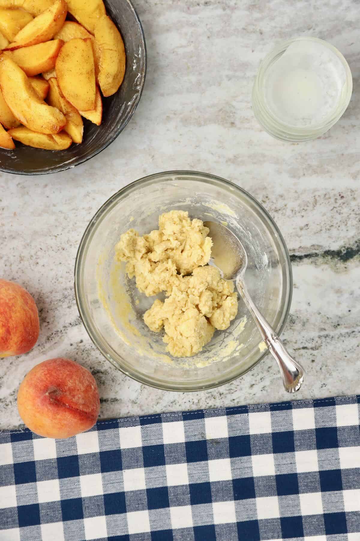 Peach cobbler dough with flour, cornmeal, sugar, and butter.