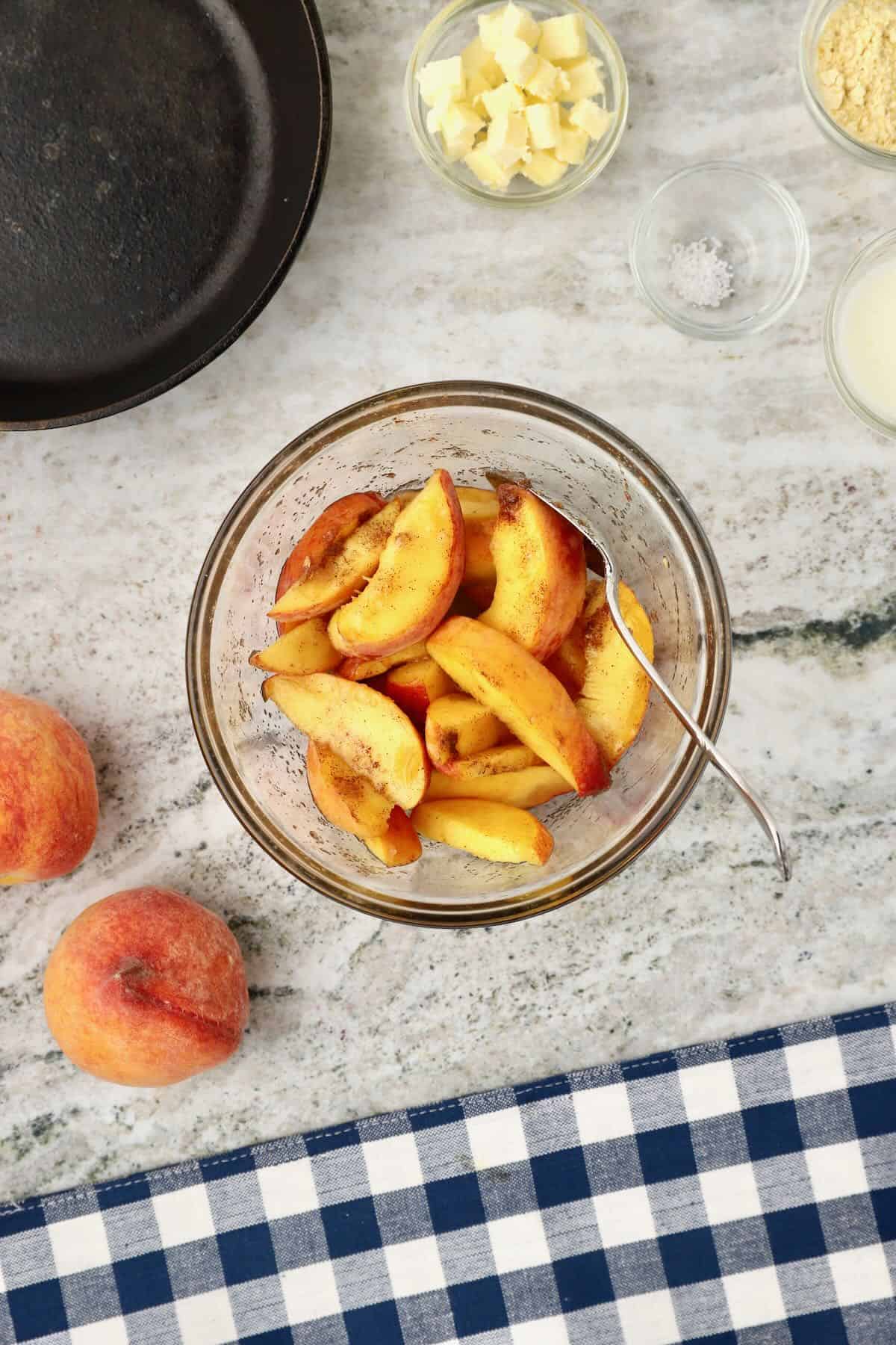 Sliced peaches in a bowl, coated with sugar.