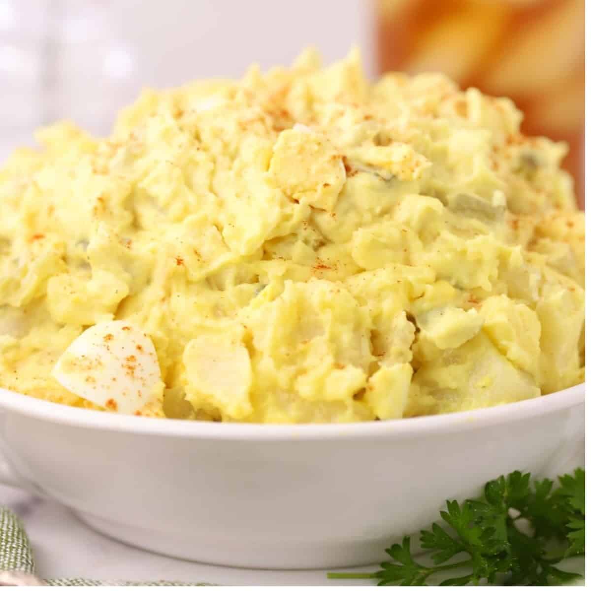 A white bowl full of creamy Southern Potato Salad.