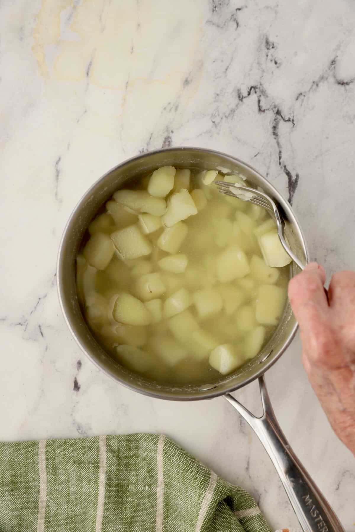 A saucepan with cooked potatoes showing how to tell when they are done.