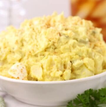 A large bowl of classic Southern Potato Salad, garnished with paprika.
