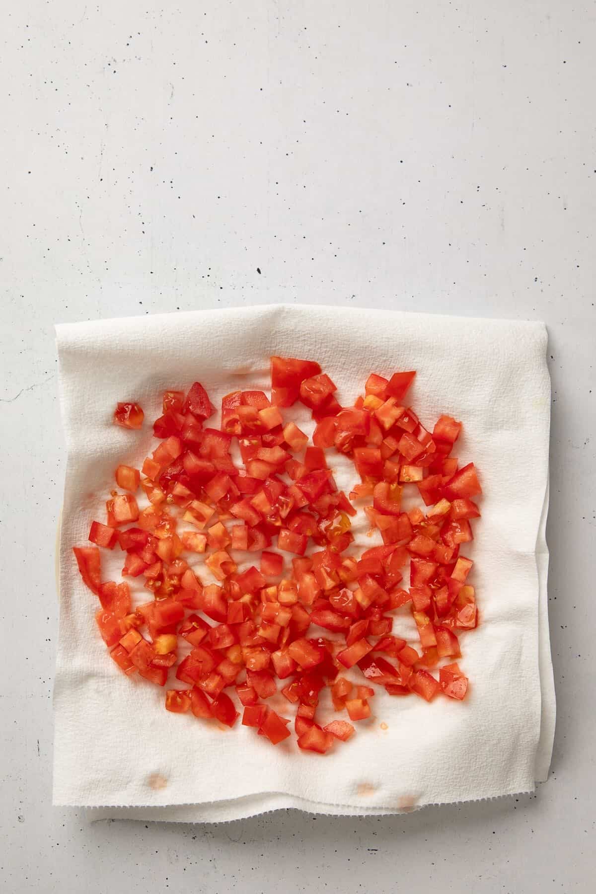 A tomato chopped up, draining excess moisture on paper towels.