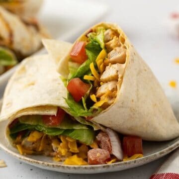 Grilled chicken wrap cut in half with grilled chicken, chipotle mayo, lettuce, tomato, and shredded cheese.