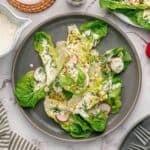 A large serving of little gem salad topped with coconut ranch dressing and sliced radishes.