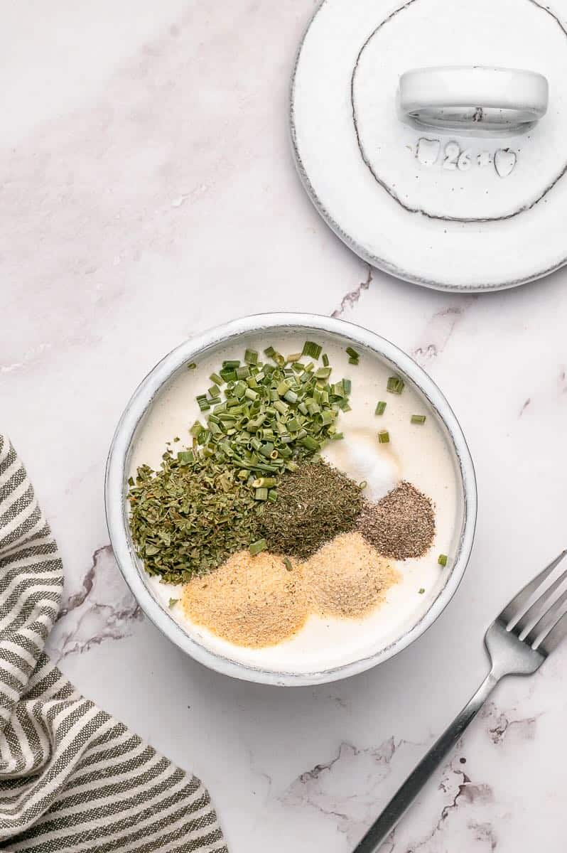 Dried seasonings added to the coconut milk mayonnaise mixture in a bowl.