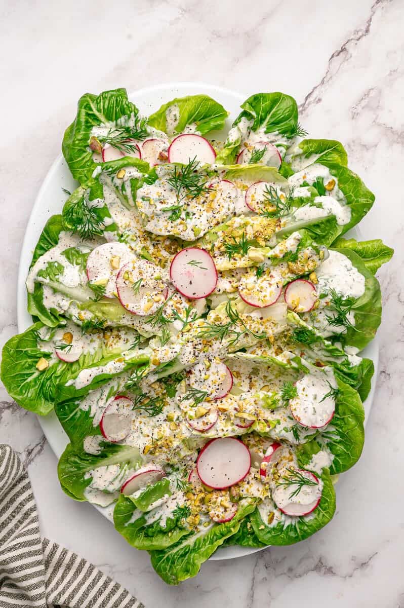 Little Gem Salad with Coconut Ranch Dressing topped with pistachios and fresh dill.