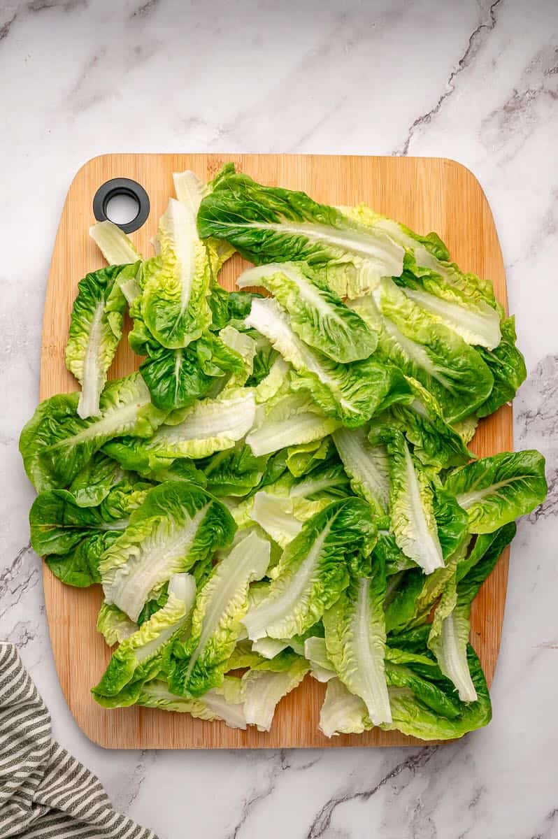 Washed Little Gem lettuce leaves spread out on a cutting board.