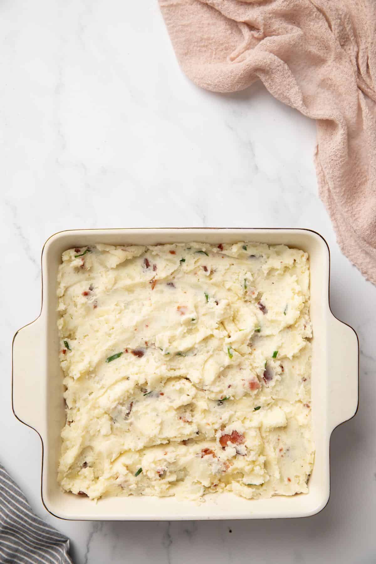 Twice Baked Potato Casserole in a square baking dish, ready for the oven.
