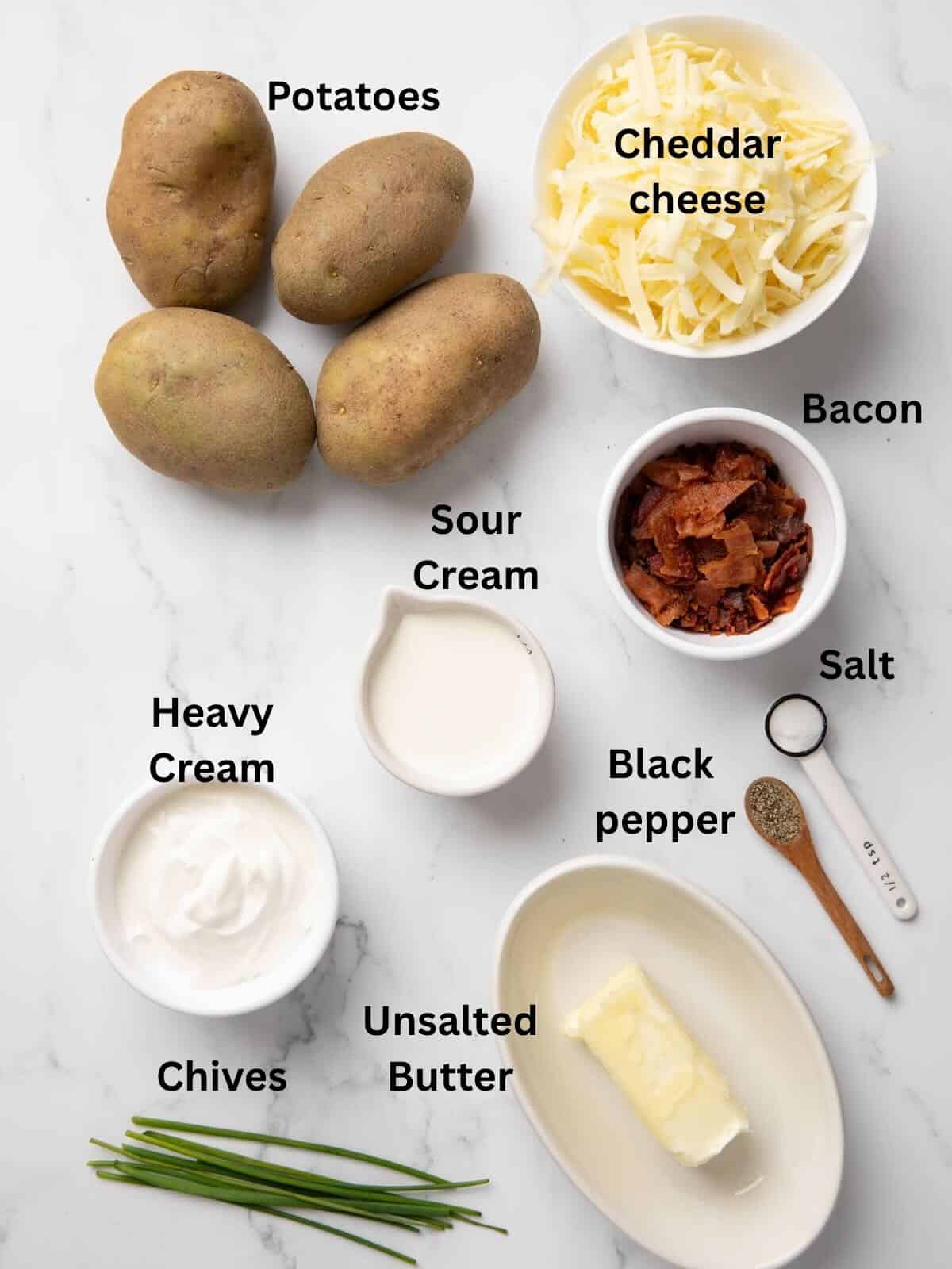 Ingredients to make Twice Baked Potato Casserole includes baking potatoes, heave cream, sour cream, cheese, and bacon.
