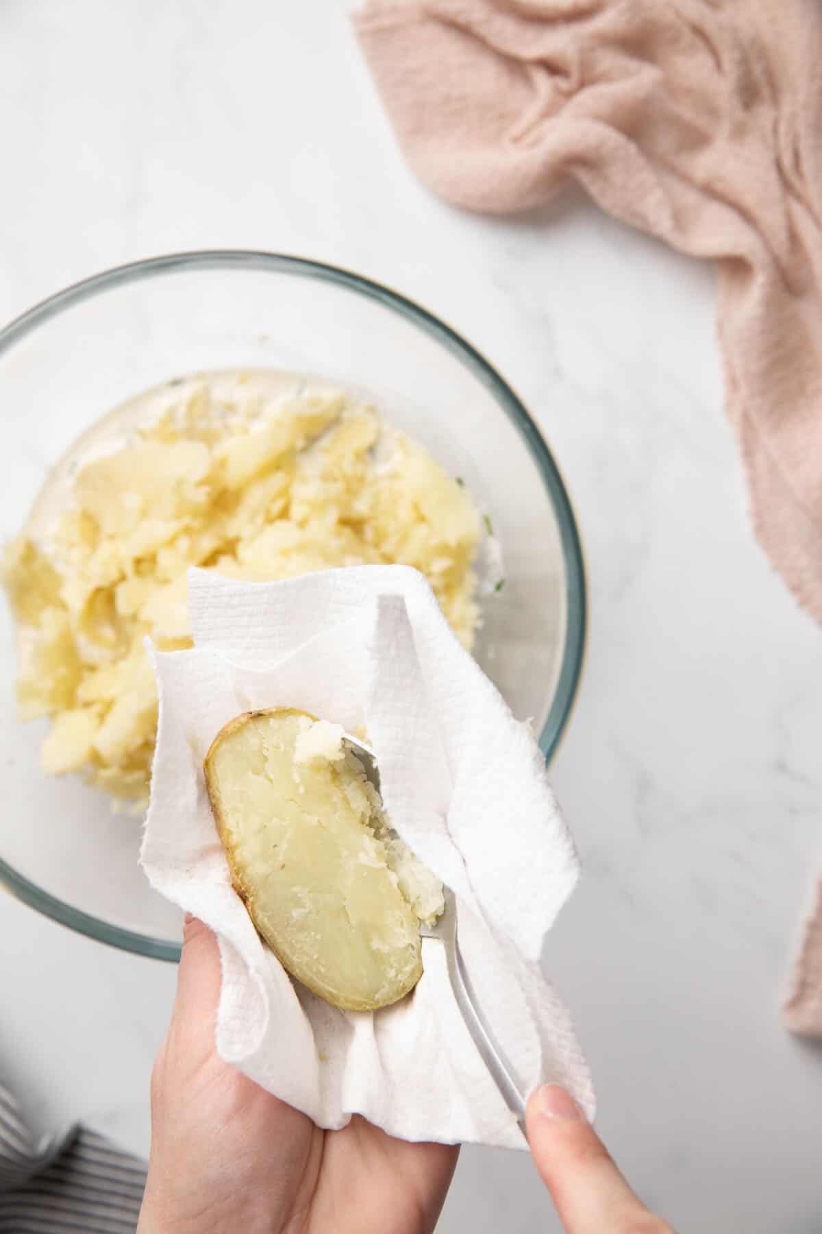 Using a spoon to scoop out the flesh of a baked potato.