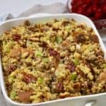 Cornbread dressing with sausage and pecans in a white baking dish.