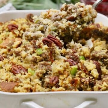 Baked cornbread dressing with sausage and pecans with a spoonful.