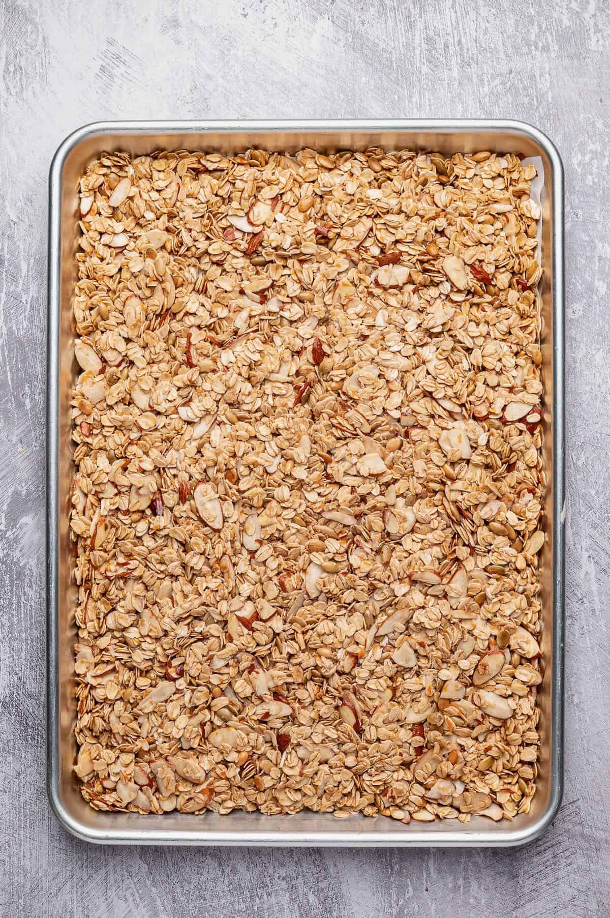 Cranberry orange granola on a baking sheet ready to be baked.