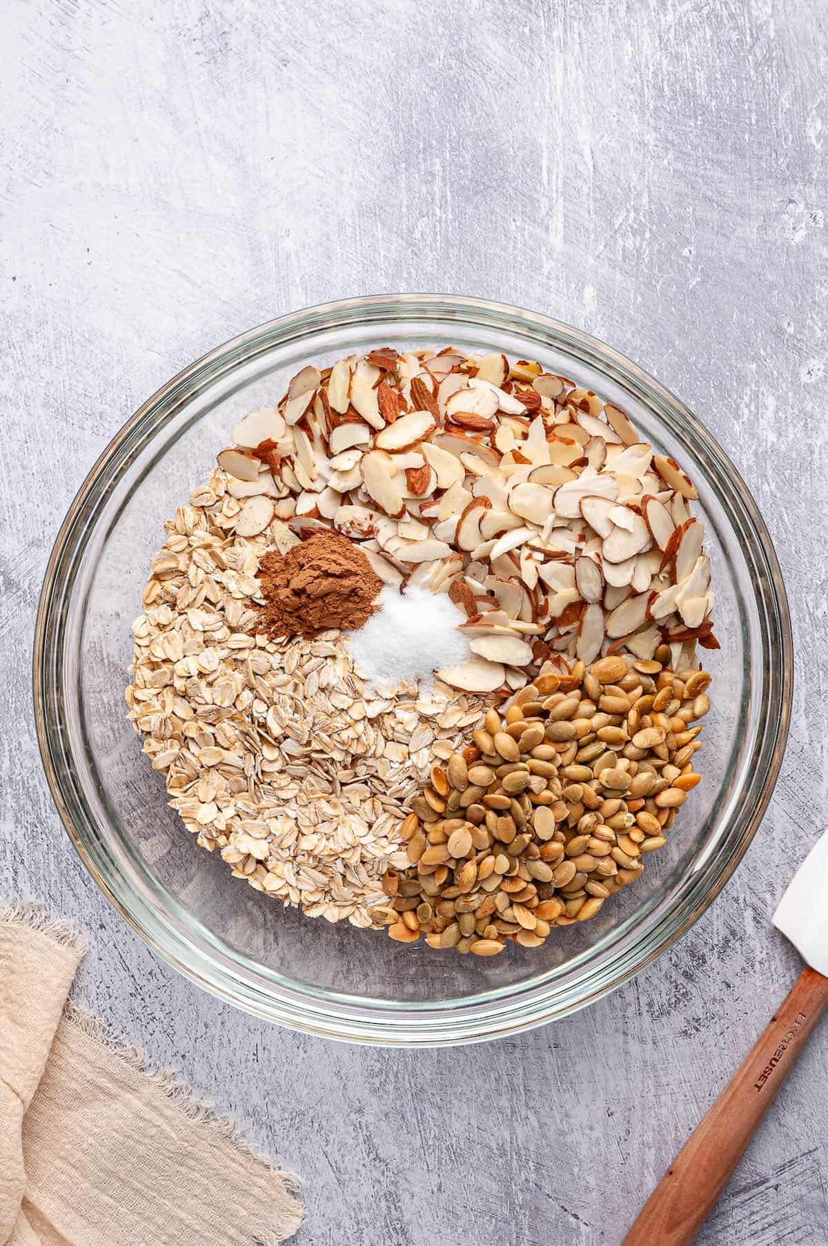 Oats, almonds, pumpkin seeds, and cinnamon in a bowl.