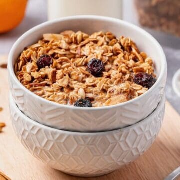 Cranberry orange granola in a white bowl with milk and a spoon.
