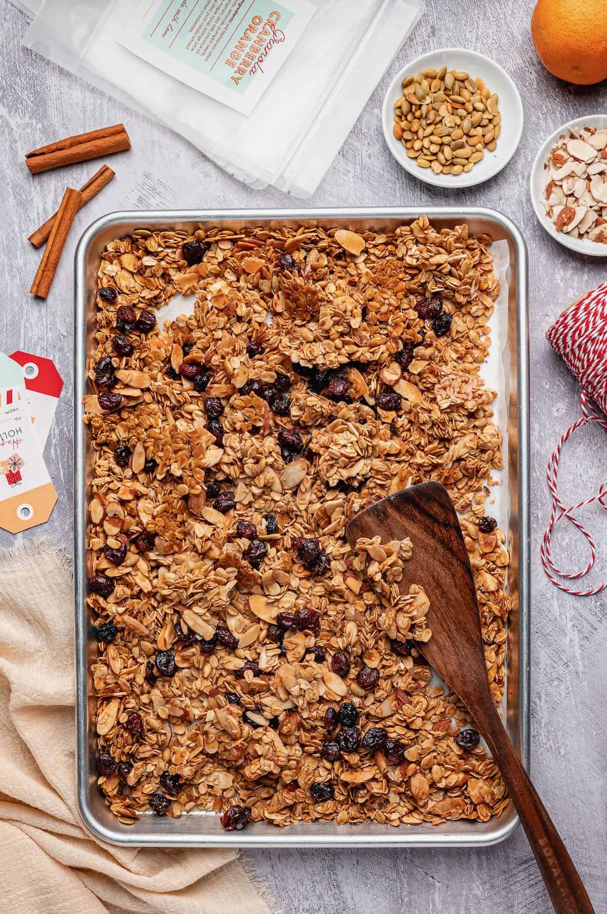 Baked cranberry orange granola topped with dried cranberries in a baking sheet.