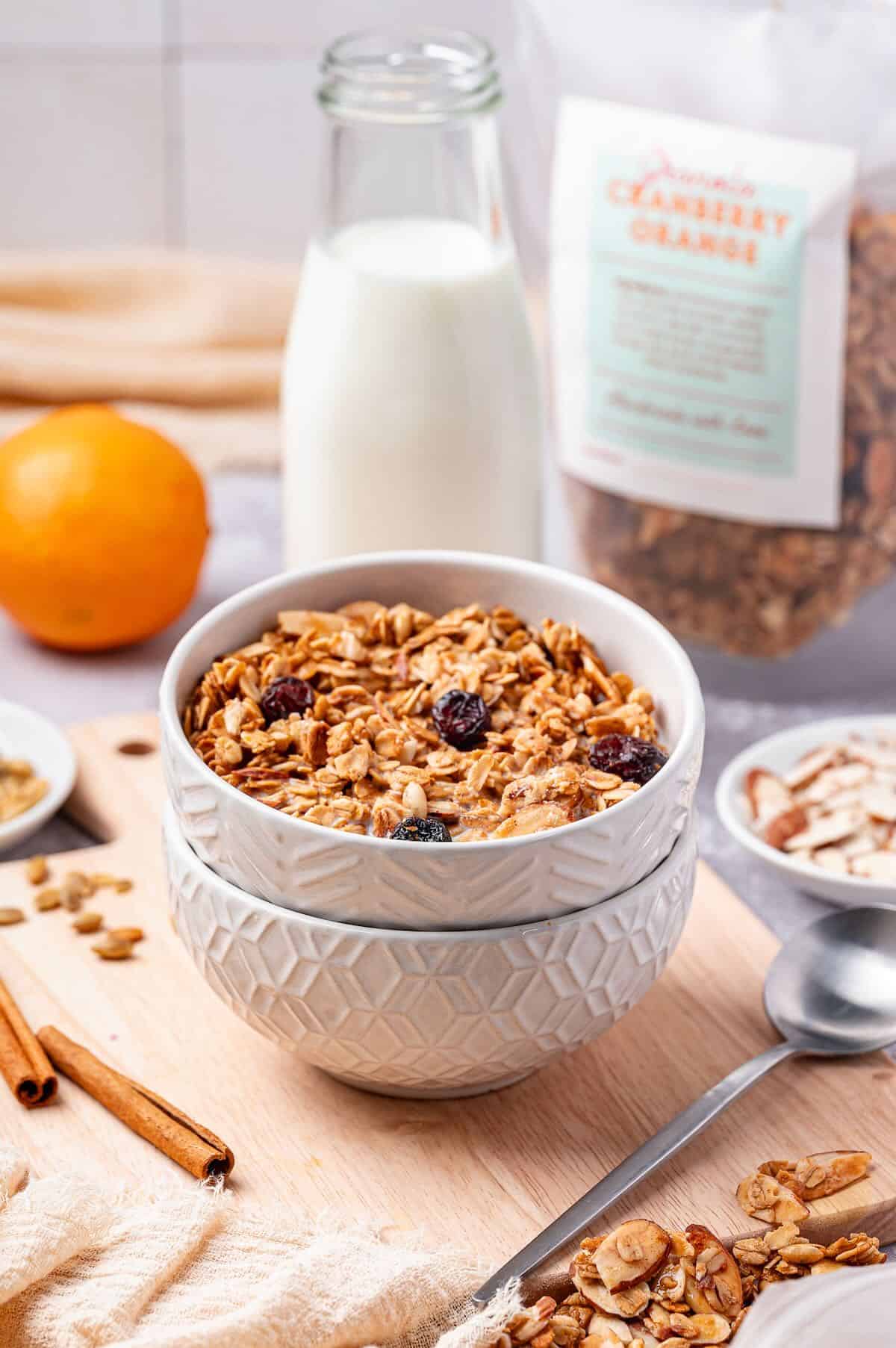 Cranberry orange granola in a bowl with a container of milk.