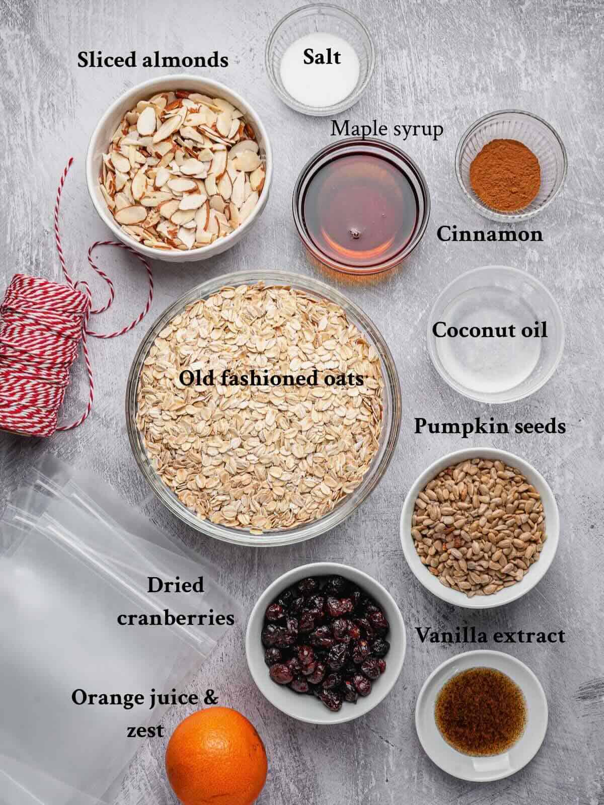 Ingredients to make cranberry orange granola arranged on a counter, plus text.