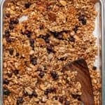 Golden brown cranberry orange granola on a baking sheet topped with dried cranberries.