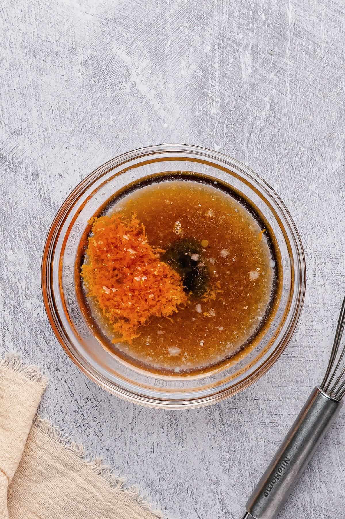 Maple syrup, vanilla extract, coconut oil, orange juice and orange zest in a bowl.