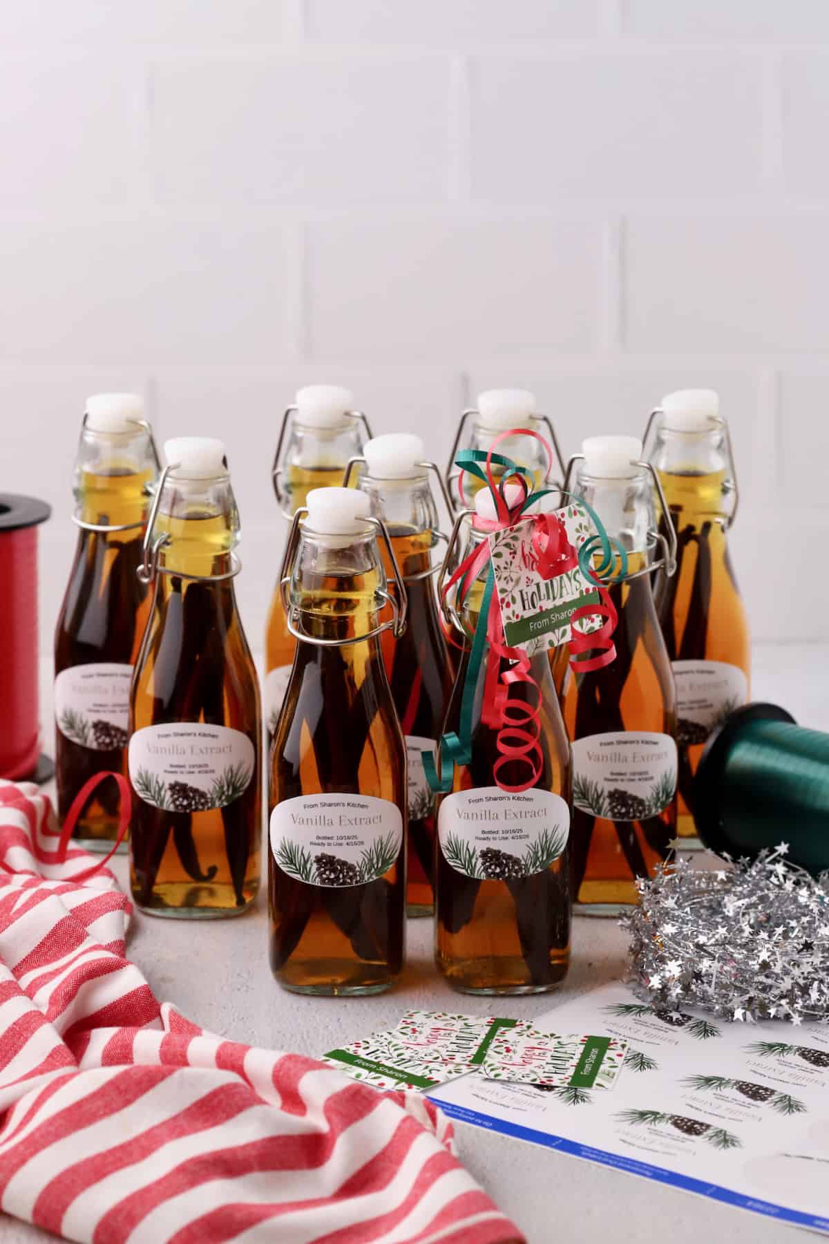 Ten bottles of homemade vanilla extract with labels and festive gift tags.