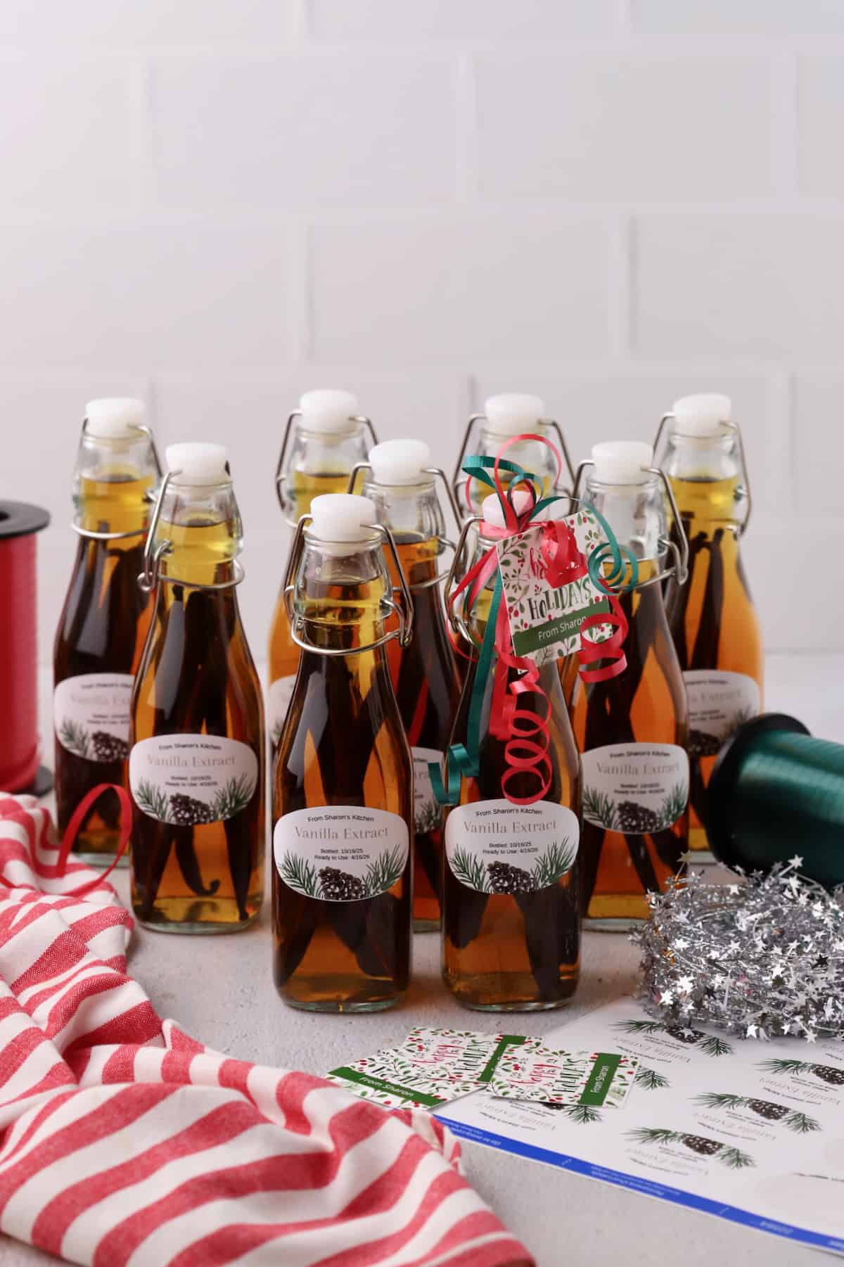 Ten glass jars full of vanilla extract ready for gifting.