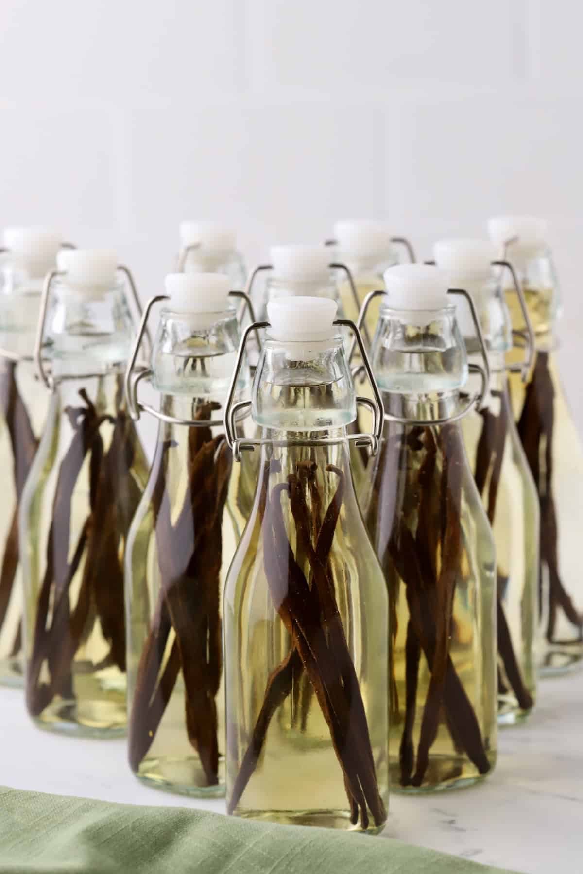 Ten glass jars with vanilla beans, vodka, and bourbon ready to steep for 8 weeks.